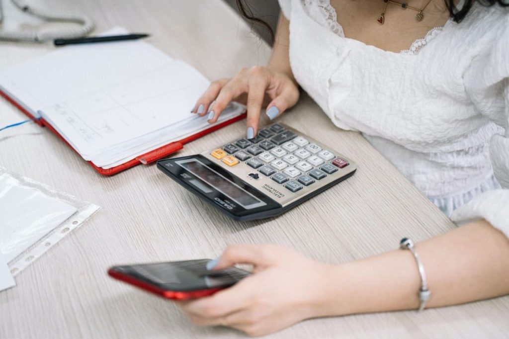 Pessoa preenchendo declaração de imposto de renda com calculadora e documentos financeiros, representando a dedução de despesas com plano de saúde.